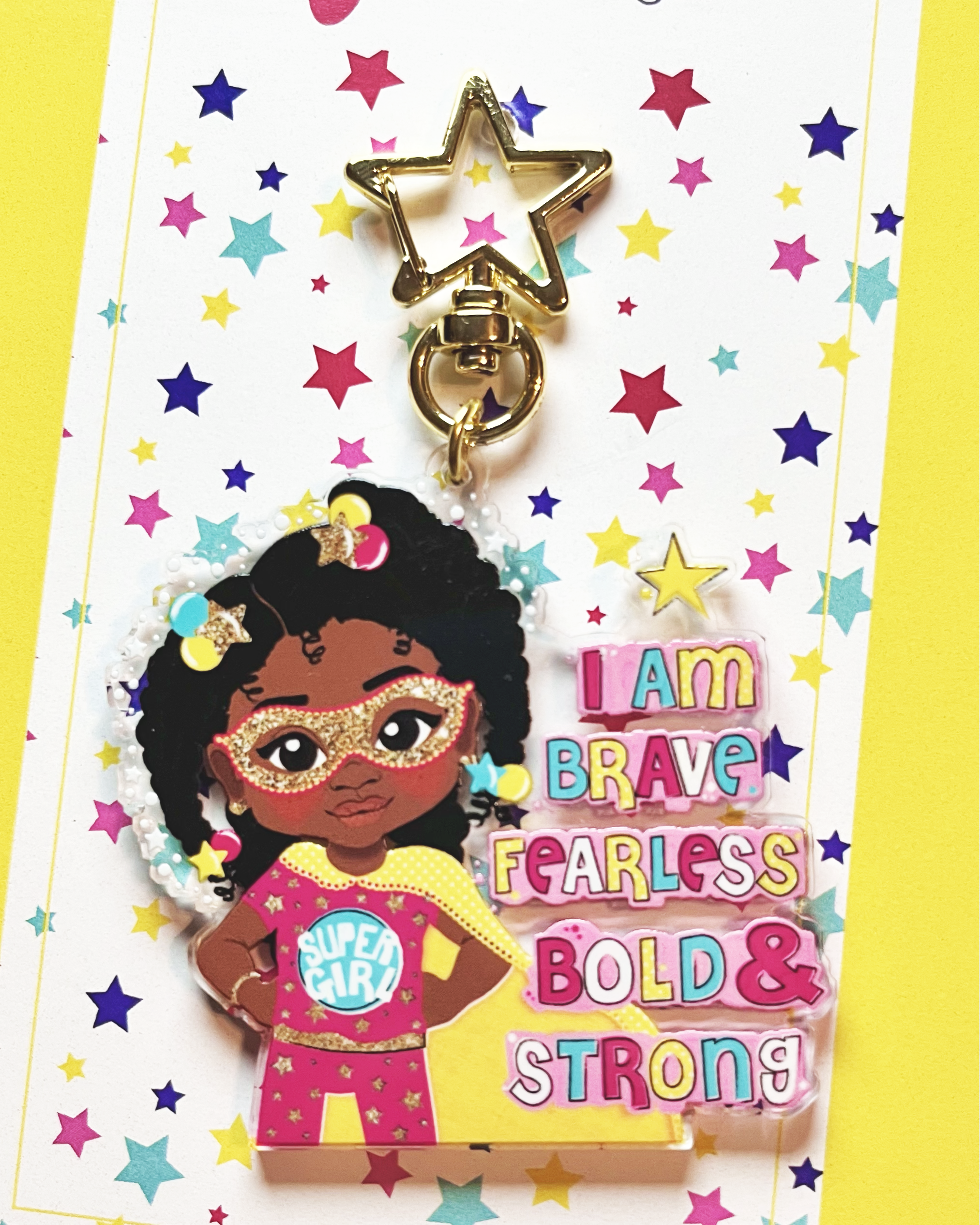 Keychain with superhero-themed character on a colorful star-patterned card, featuring the brand 'fefus Designs'.