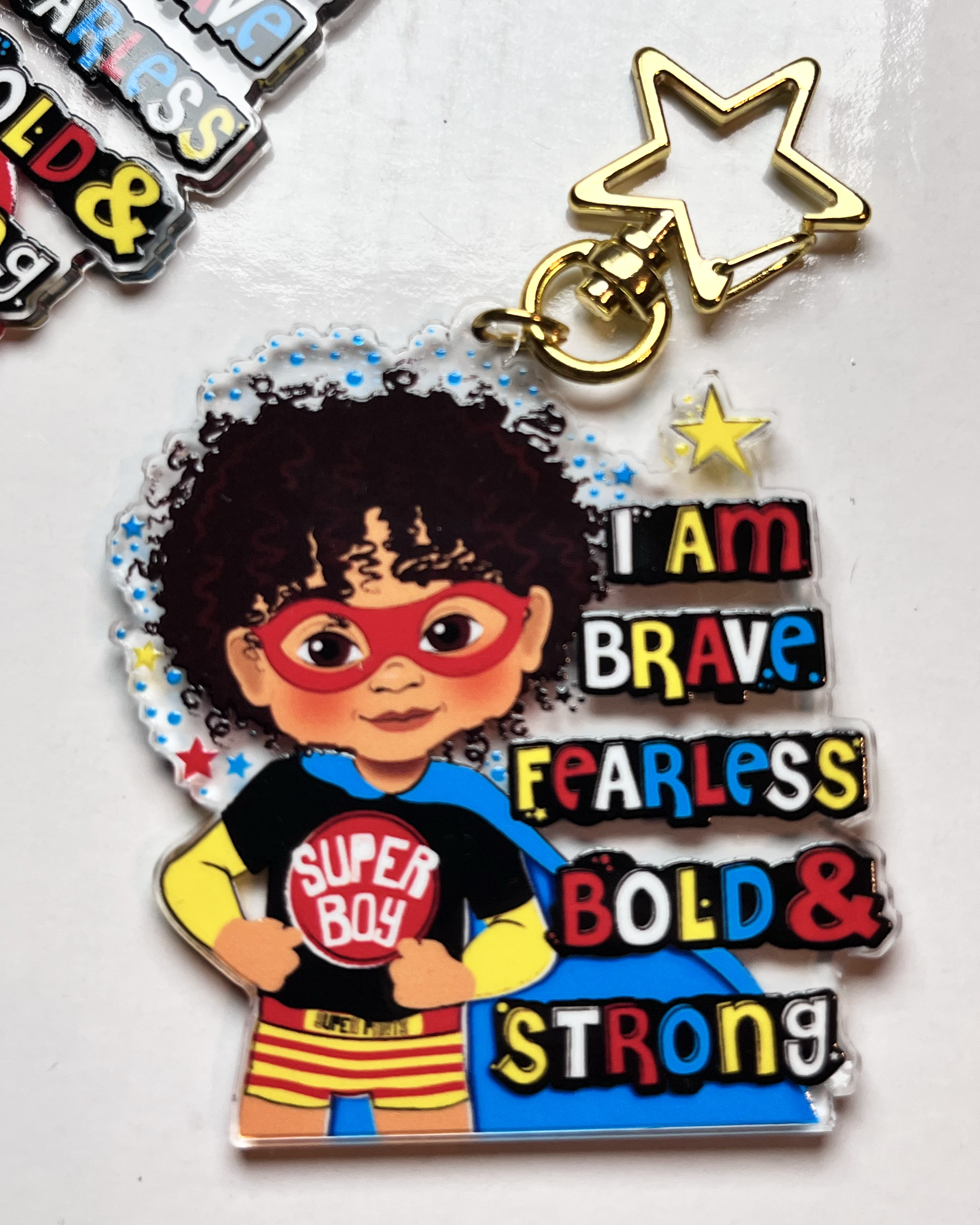 Keychain with superhero-themed character and motivational text on a white background