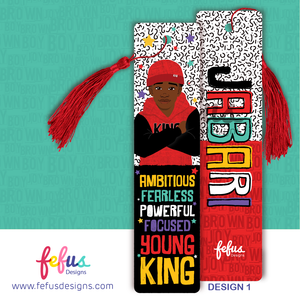Two rectangular bookmarks with red tassels. One features an illustration of a person in a red beanie and hoodie with the text AMBITIOUS FEARLESS POWERFUL FOCUSED YOUNG KING. The other displays the name JABARI in large colourful letters.