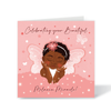 A square pink greeting card featuring an illustrated Black child with angel wings, a floral headband, and the text 'Celebrating your Beautiful' and 'Melanin Miracle!'. The card is shown standing against a clean white background.