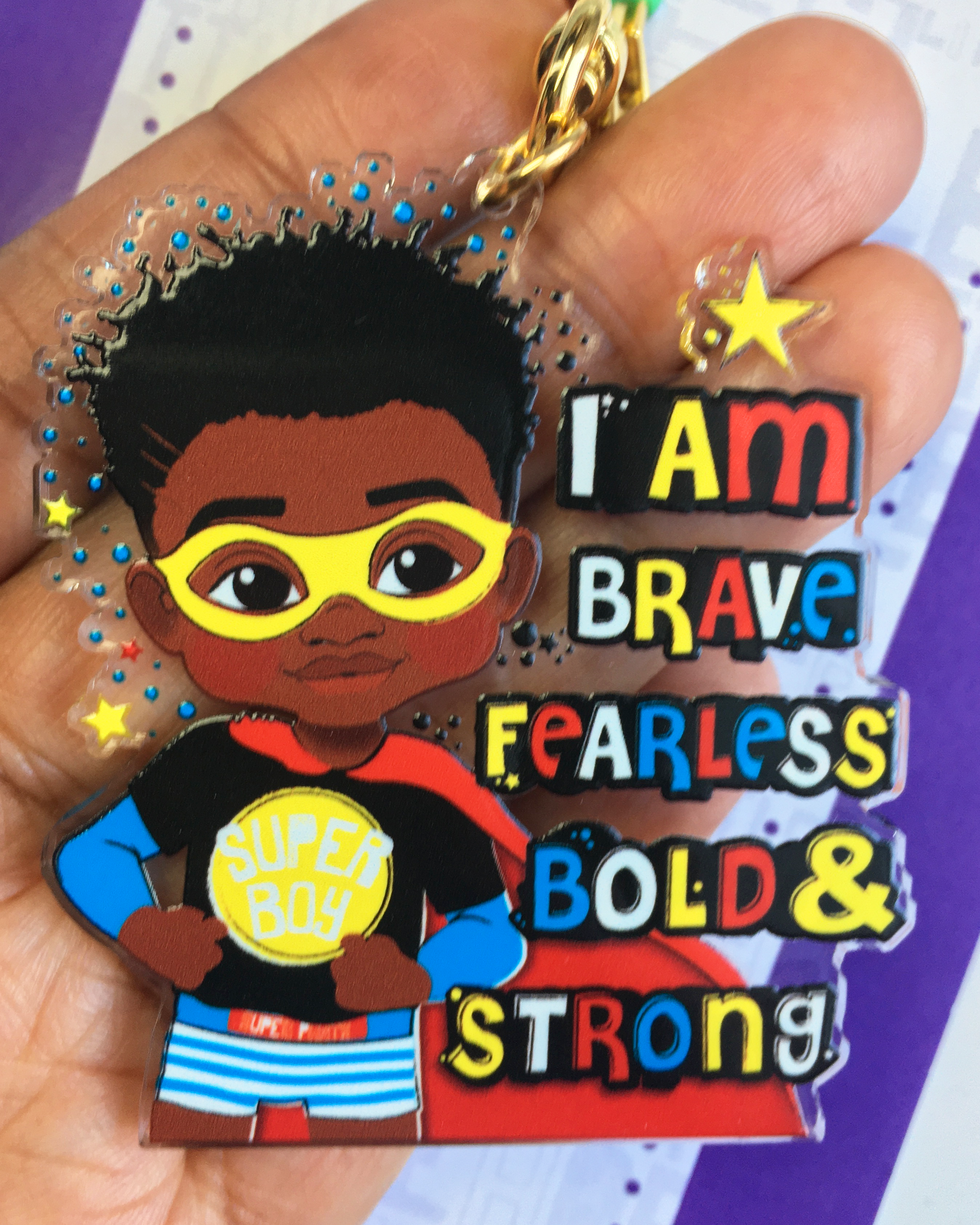Keychain with a cartoon character holding a sign saying 'I am brave, fearless, bold & strong' on a hand.