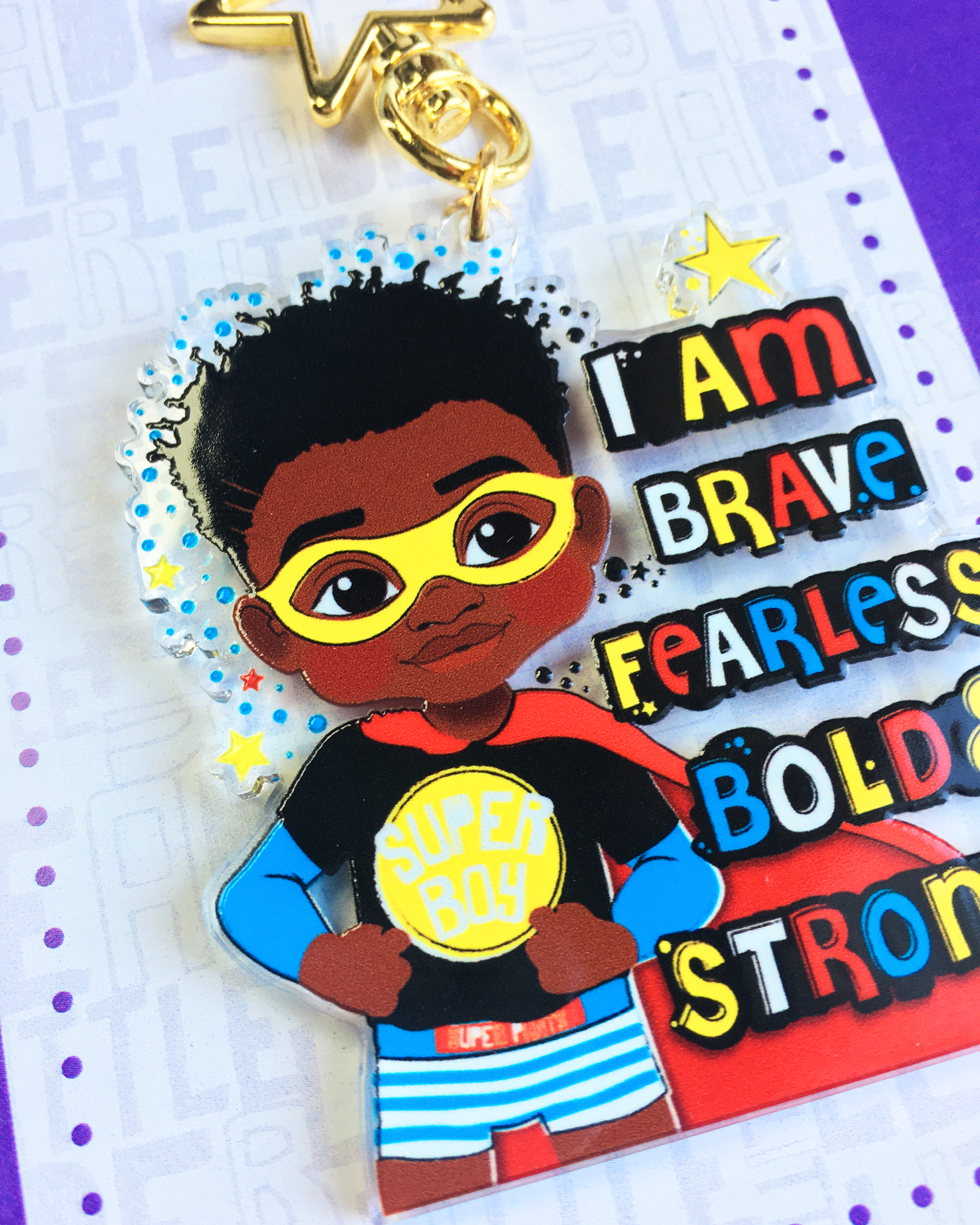 Keychain with black boy superhero design and motivational text on a multicoloured background