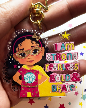 fefus designs brown_girl superhero keyring / Keychain with cartoon character and motivational text held by a hand