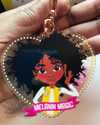 Heart-shaped keychain with a Black Afro Girl hand drawn  character and 'Melanin Magic' text on a banner scroll. Black tween / teen Girl  keyring with curly afro and “Melanin Magic” affirmation