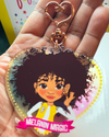 Heart-shaped keychain with a Mixed race Afro Girl hand drawn  character and 'Melanin Magic' text on a banner scroll. Brown tween / teen Girl  keyring with curly afro and “Melanin Magic” affirmation