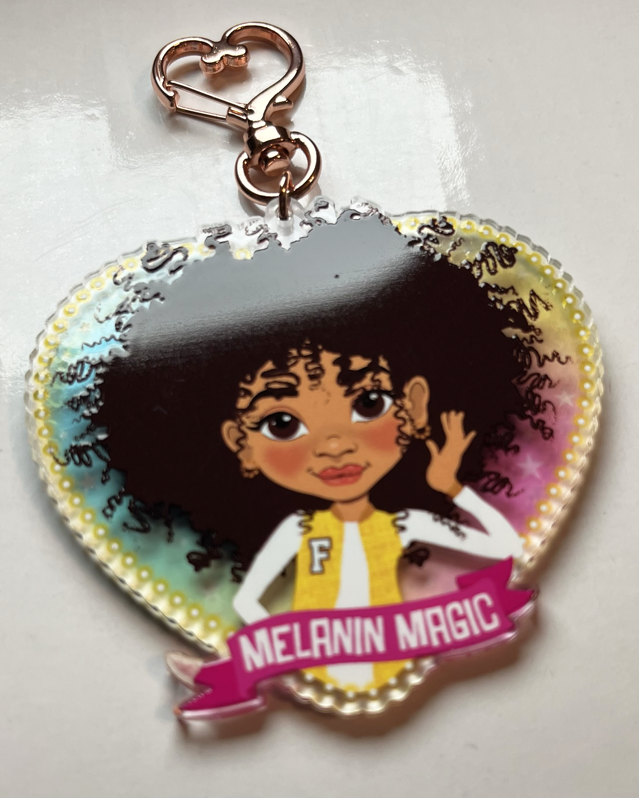 Heart-shaped keychain with a Mixed race Afro Girl hand drawn  character and 'Melanin Magic' text on a banner scroll. Brown tween / teen Girl  keyring with curly afro and “Melanin Magic” affirmation