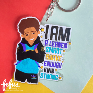 Brown boy affirmation keyring featuring a stylish young boy wearing a blue and black tracksuit by Fefus Designs