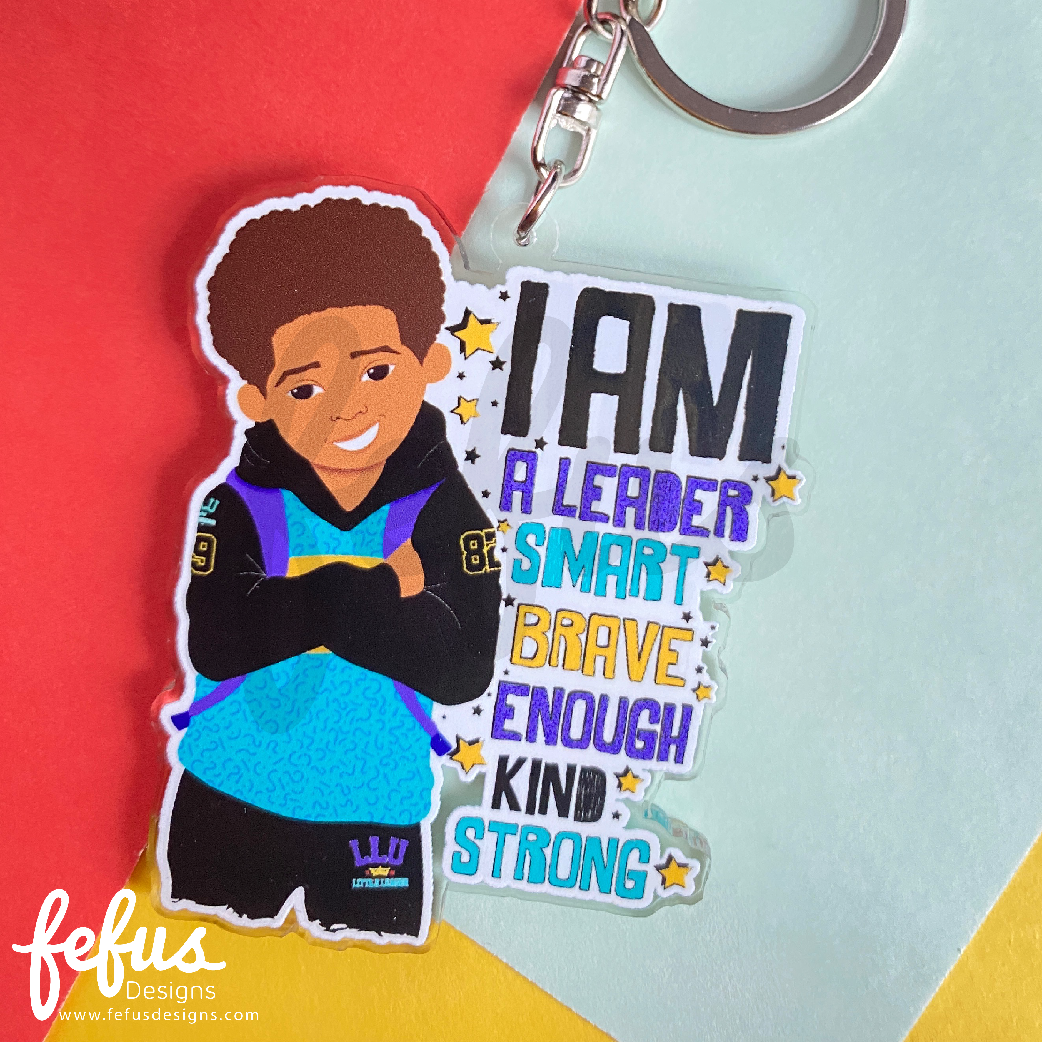 Brown boy affirmation keyring featuring a stylish young boy wearing a blue and black tracksuit by Fefus Designs